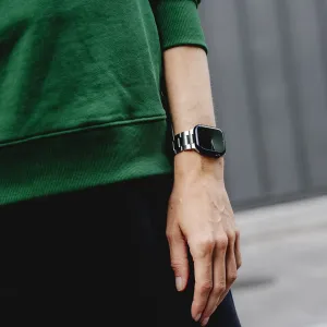 KeyBudz Apple Watch-rem i rustfritt stål på håndleddet, vist med en svart smartklokke og sølvfarget metall-lenkerem.