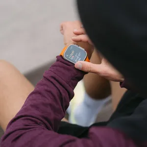 KeyBudz Journey Apple Watch-reim i elektrisk oransje på håndleddet, vist med Apple Watch under en treningsøkt.