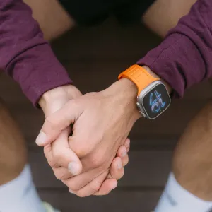 KeyBudz Journey oransje Apple Watch-rem på et håndledd, vist på en smartklokke mens noen holder hender.