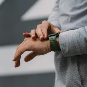 KeyBudz Journey Apple Watch-armband i skogsgrönt på en handled med en svart klockboett.
