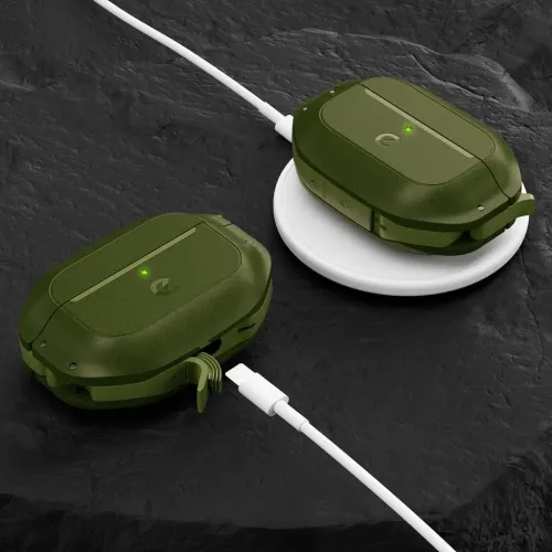 Skovgrønt AirPods Pro 2-etui, en på trådløs opladningsplade og en med åbent portdæksel og kabel ved siden af på sten.