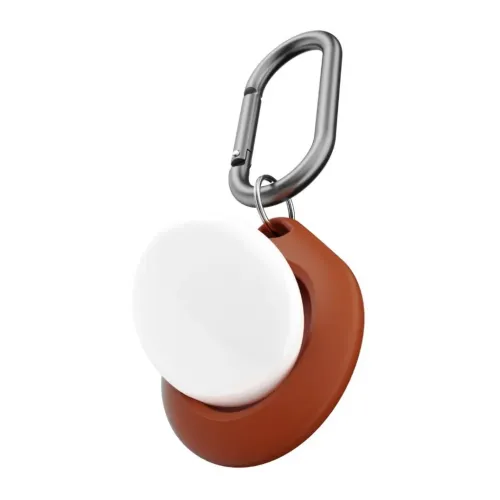 Ruskea AirTag-pidike, jossa on pyöreä aukko ja upotettu valkoinen AirTag, joka on kiinnitetty metallikarabiiniin valkoista neutraalia taustaa vasten.