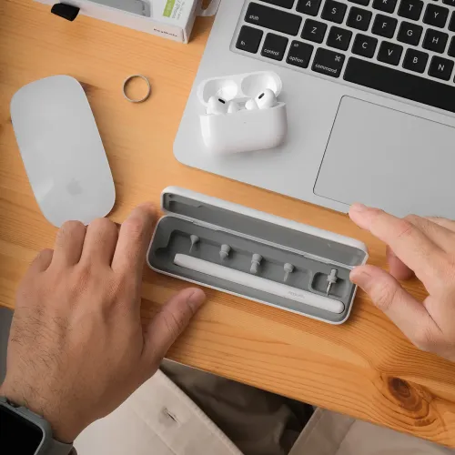 AirCare 2.0-rengøringssæt i åbnet etui med pen og fem spidser på rad og række, på skrivebordet ved siden af den bærbare computer, åbne AirPods og mus.