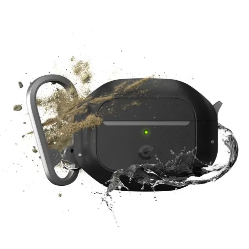 Sort AirPods 3-etui med LED på forsiden og karabinhage i metal, set forfra i en vinkel, omgivet af vandsprøjt og hvirvlende sand.