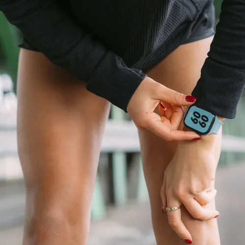 KeyBudz Journey Apple Watch-armbånd i Tidal Blue på en Apple Watch, når en hånd justerer klokken i nærbilde med store tall.