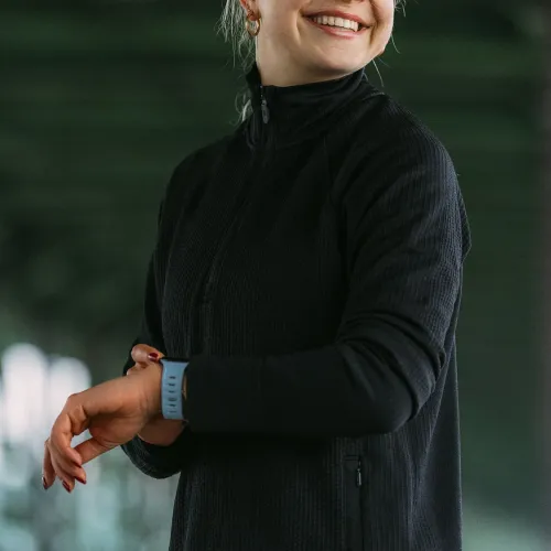 KeyBudz Journey Apple Watch-armbånd i tidevannsblått på håndleddet, perforert bånd med rader av hull, bæres i svart genser.